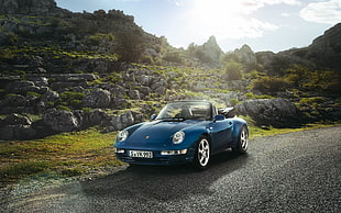 blue Porsche convertible coupe on gray concrete road during day time