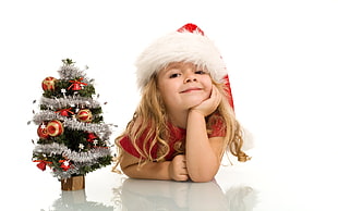 girl wearing Santa costume beside Christmas Tree