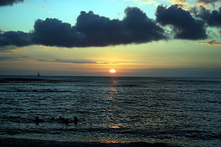 rippling ocean under cloudy sky during sundown