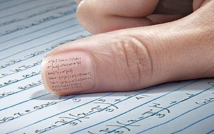human thumb with mathematical equation written on nail