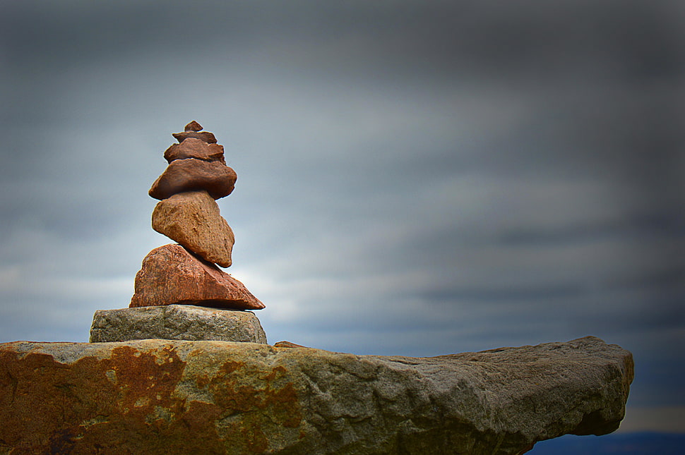 pile of brown rocks under cloudy sky HD wallpaper