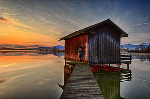 Man standing beside floating house with brown wooden bridge during sunset