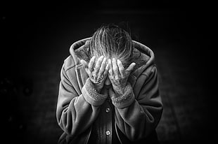 grayscale photography of person wearing button-up hoodie covering face