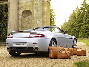 gray Aston Martin Vantage coupe near brown leather bags photo taken during daytime