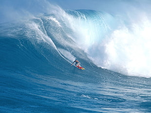 person riding surfboard under ocean wave during daytime