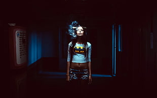 woman in white Batman portrait long-sleeved crop top while smoking