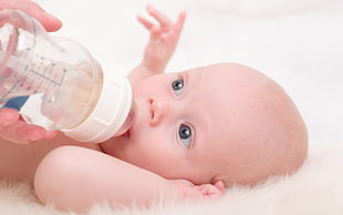 baby and white feeding bottle