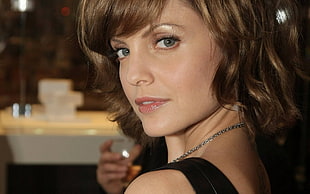 close up photo of woman wearing silver-colored necklace and black sleeveless top