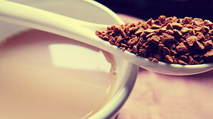 ground coffee on white ceramic spoon near cup