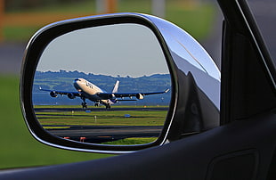 blue and white airbus reflected on side mirror