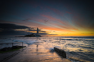 photography of seashore facing white lighthouse during golden hour