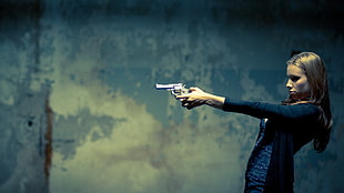 woman holding gray revolver pistol