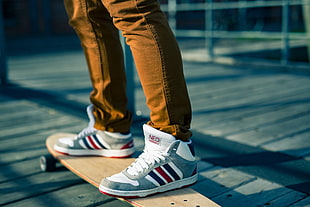 selective focus photography of Adidas Neo sneakers with brown longboard