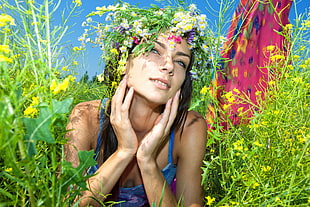 woman wearing blue spaghetti strap top pron on the grass with flower headband during daytime