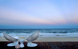 two white egg chair facing seashore