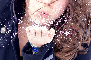 woman blowing snows on her palm