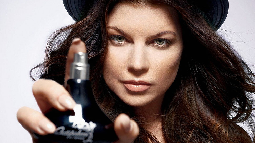 woman holding black glass fragrance bottle HD wallpaper