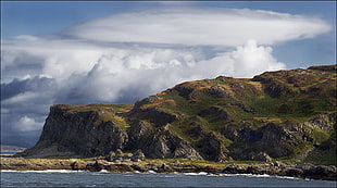 mountain ranges beside sea under white sky