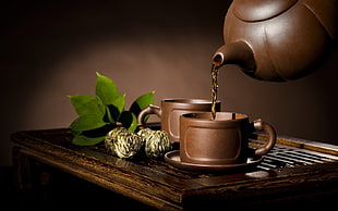 photo of brown ceramic kettle with two brown ceramic teacups