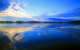 reflection of white clouds and blue sky on water under white clouds and blue sky