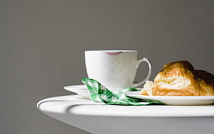 white ceramic mug beside bread on top of table