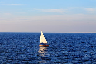 photo of a white and brown sail boat on body of water