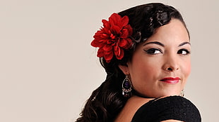 woman wearing black tops with red dahlia flower on right ear