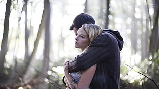 man in gray sweater hugging blonde haired woman during daytime