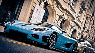 teal supercar near white building during daytime