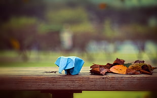 blue elephant origami on brown wooden bench with dried leaves