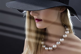 woman wearing black sun hat and white pearl necklace