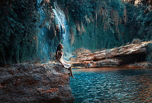 woman sit on rock infront of water photography