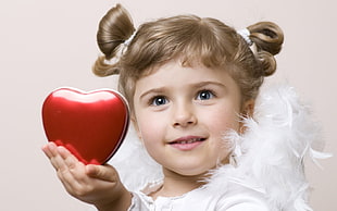girl in cherub costume holding red heart shaped case