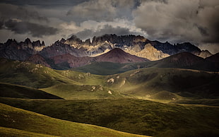 landscape photo of mountains surrounded by grass under nimbus clouds