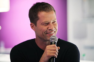 man wearing black shirt holding gray microphone on left hand