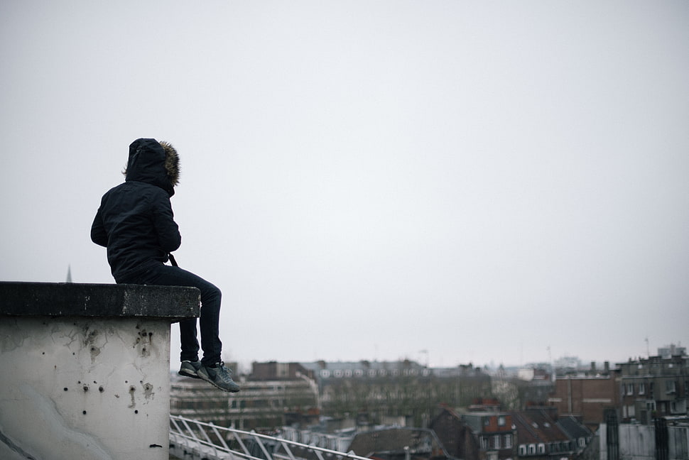 person wearing black jacket and jeans sitting on the roof during day time HD wallpaper