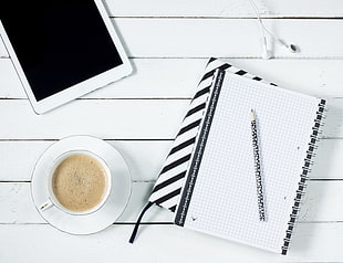 Cappuccino coffee  and white iPad and book on white surface