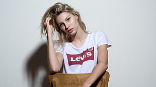 woman wearing white Levi's t-shirt standing while holding chair