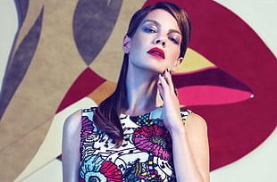 woman in multicolored floral sleeveless shirt touching her jaw