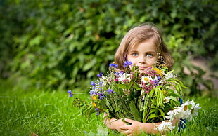 brown haired girl hiding behind patch of flowers
