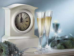white analog mantle clock beside two clear drinking glasses