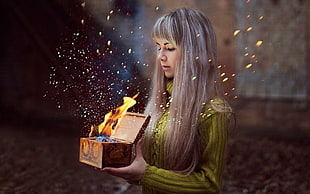 woman holding a burning wooden box chest
