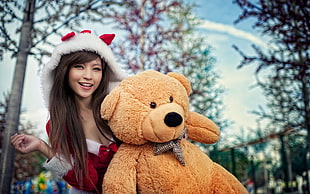 woman in Santa Claus costume with life-sized teddy bear