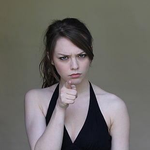 woman wearing black V-neck halter neck top pointing index finger