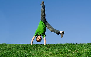 boy upside down on green field under blue sky, children