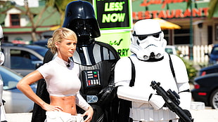 woman standing beside Darth Vader and Stormtrooper mascots at daytime