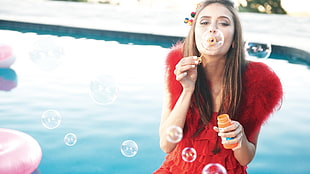 woman in red fur dress blowing bubbles