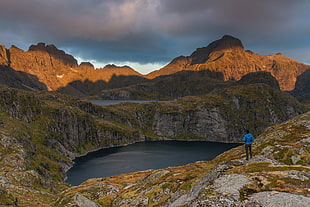 man in blue jacket and black pants standing in front lake during daytime, norway HD wallpaper