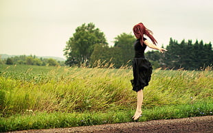 woman wearing black dress standing on green grass field
