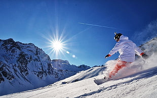 Man playing snowboard during day time on top of the mountain